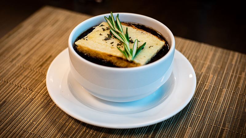 Hearty and hot French onion soup topped with toast and herbs.